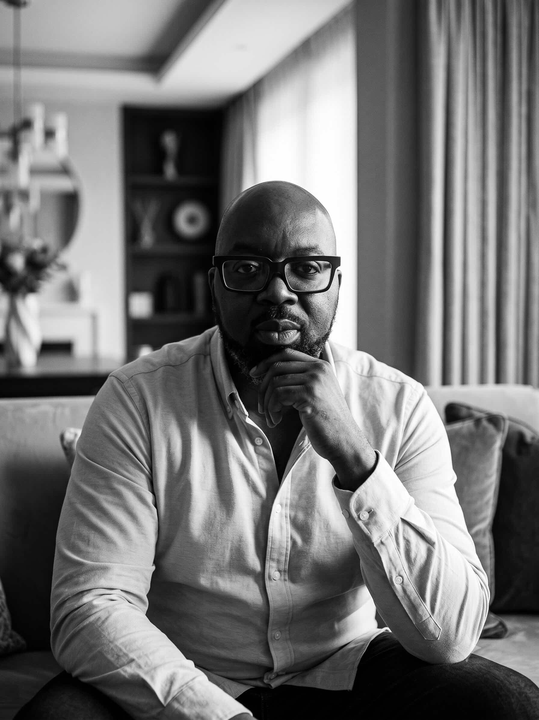 Bolaji Yoloye at home, hand resting against his chin, mid-thought